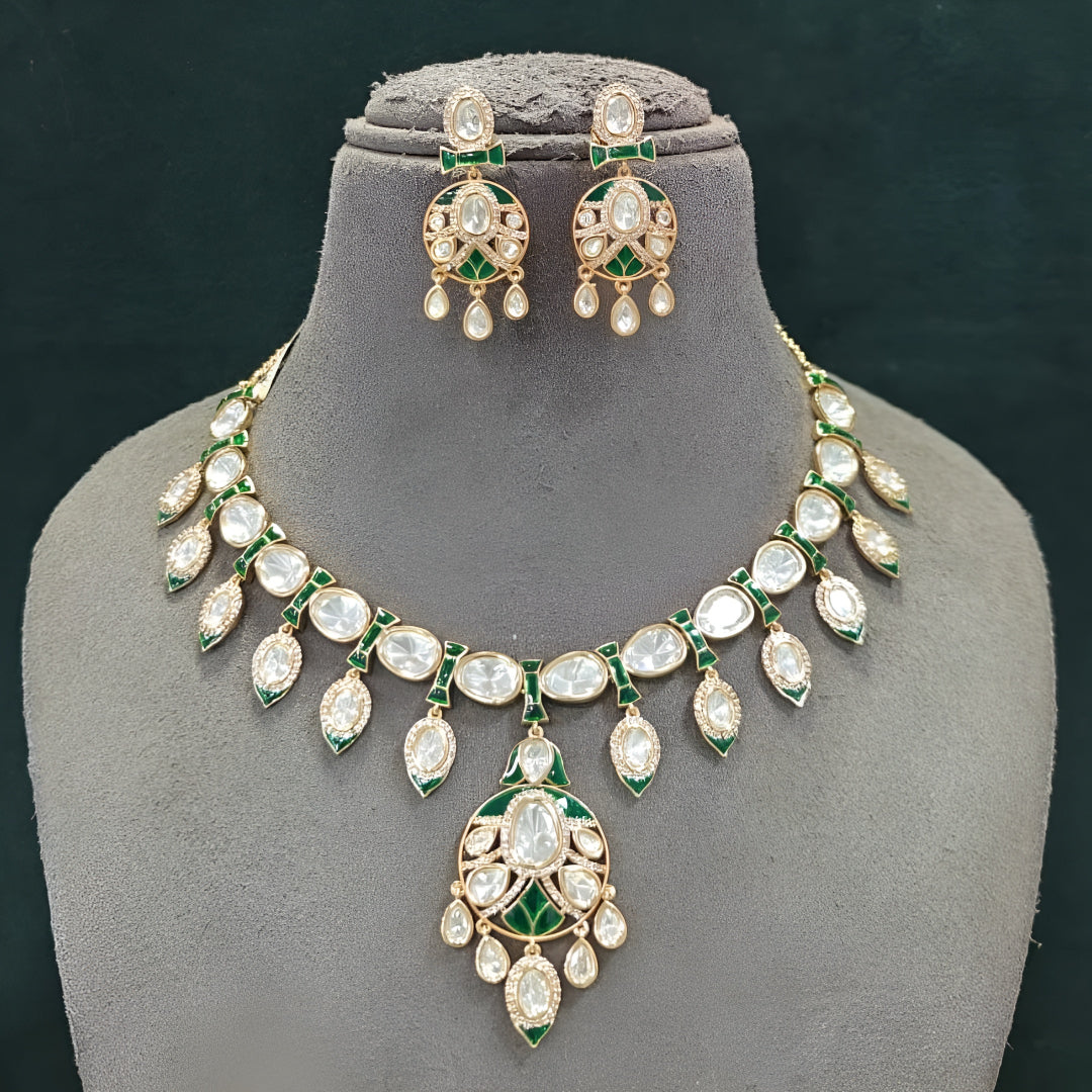 Gold-tone green meenakari kundan necklace set with round centre pendant, leaf-shaped drops and matching drop earrings on a grey display bust