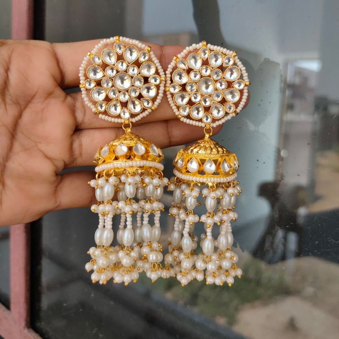 Antique gold Kundan jhumka earrings with floral stud and pearl tassel drops for women.