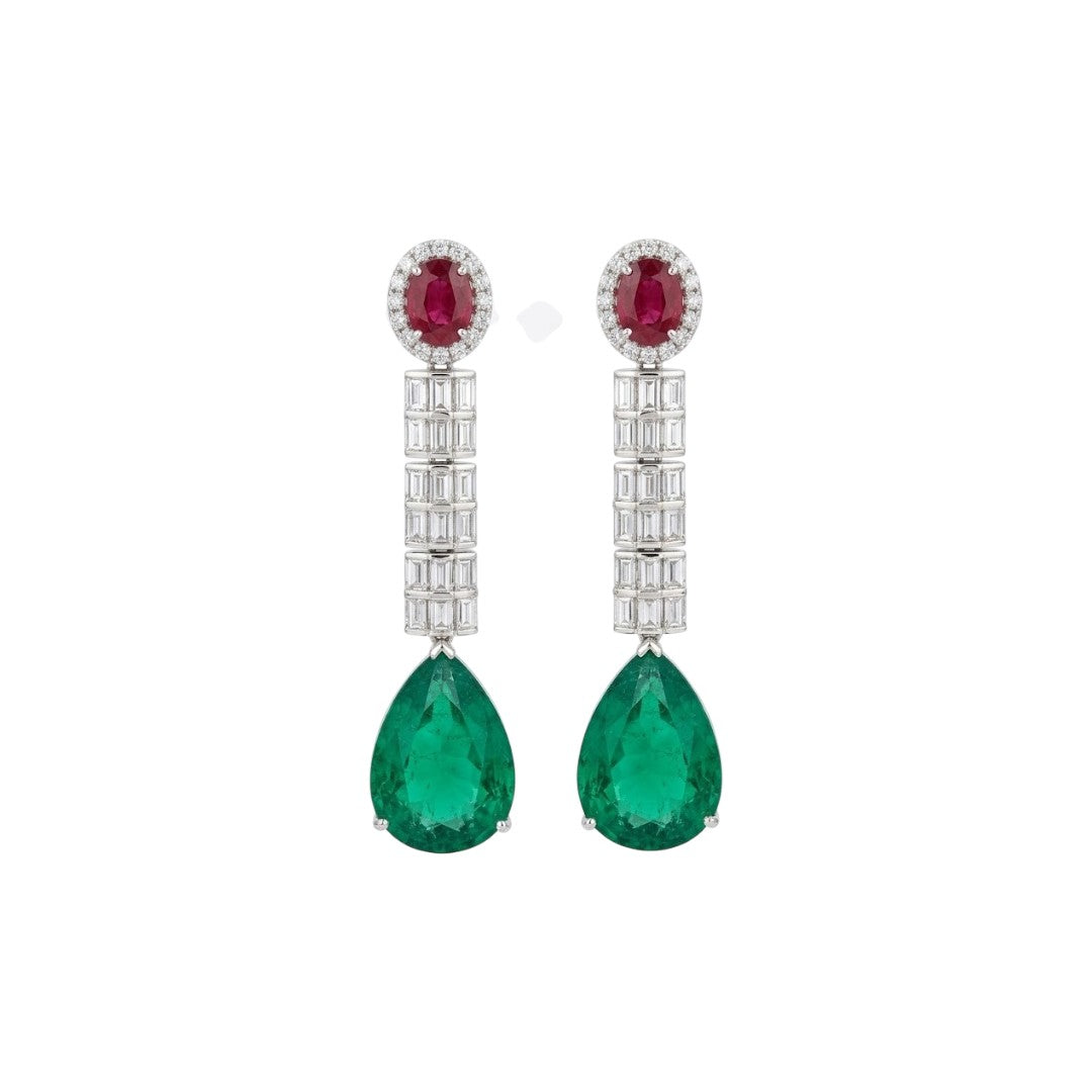 Silver-tone American diamond long drop earrings with ruby-red oval top stones, clear baguette stone rows and large emerald-green pear-cut drops on dark green velvet