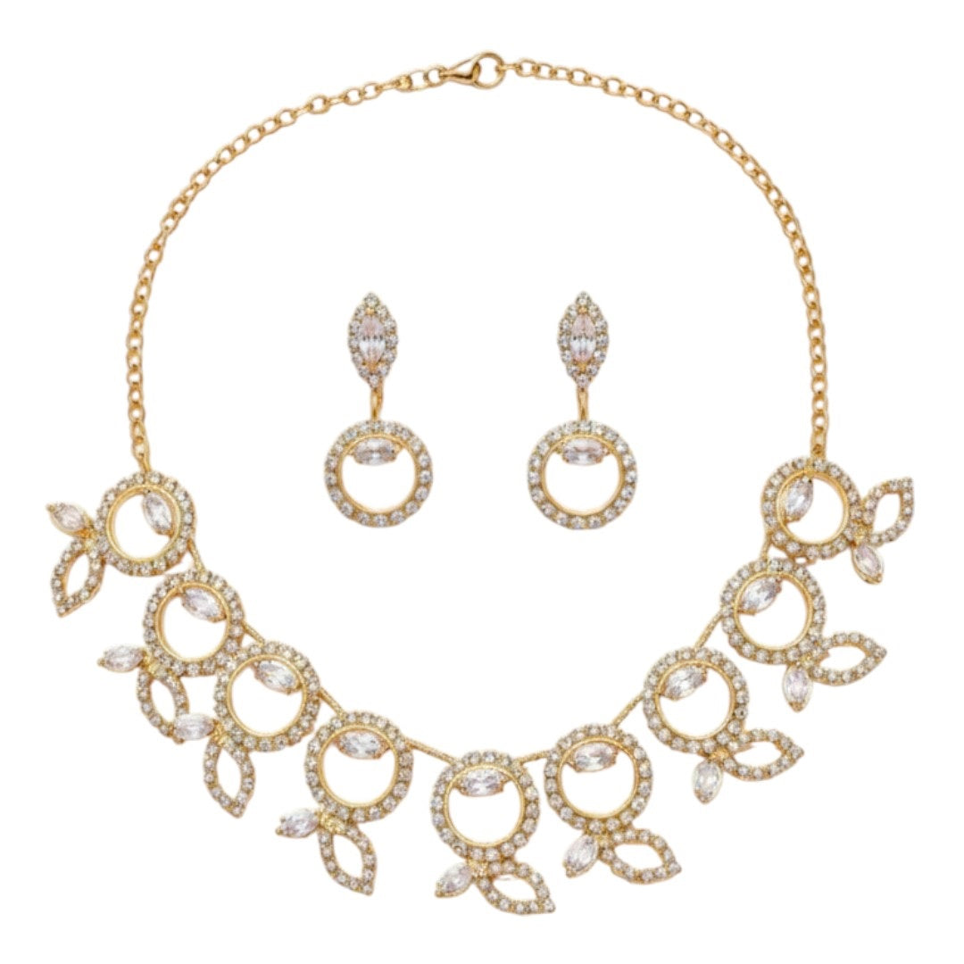 "Gold-tone necklace and earring set with circular and leaf motifs displayed on black velvet stand"