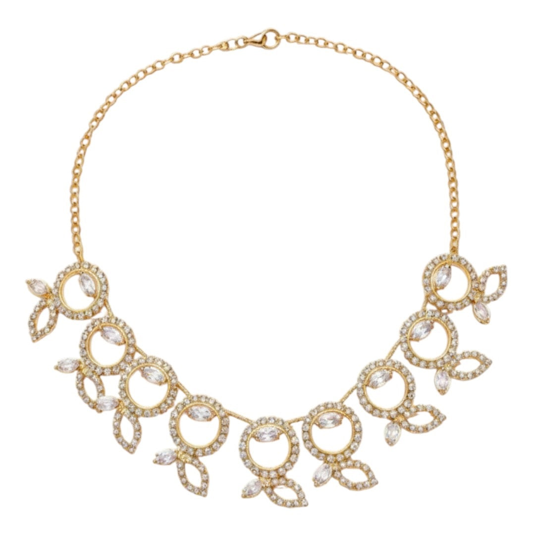 "Gold-tone necklace and earring set with circular and leaf motifs displayed on black velvet stand"