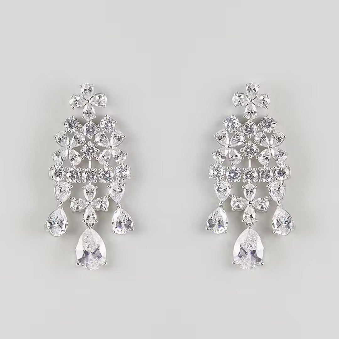 "Silver-plated floral chandelier earrings with cubic zirconia stones and pear-shaped crystal drops, product shot on grey background"