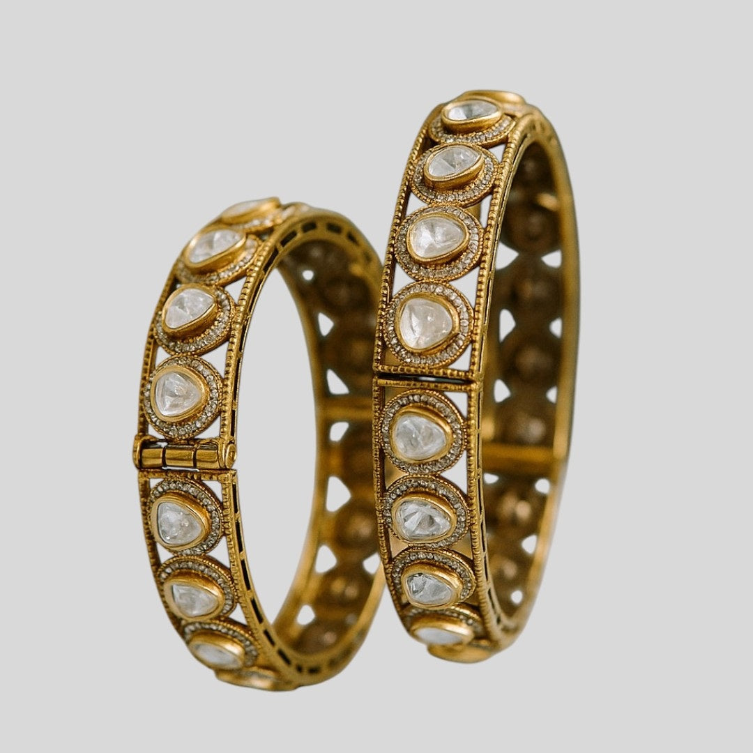 Antique Mehandi polish gold-plated bangles with dome-cut white Kundan stones, placed on a dark green fabric – traditional Indian bridal kada set