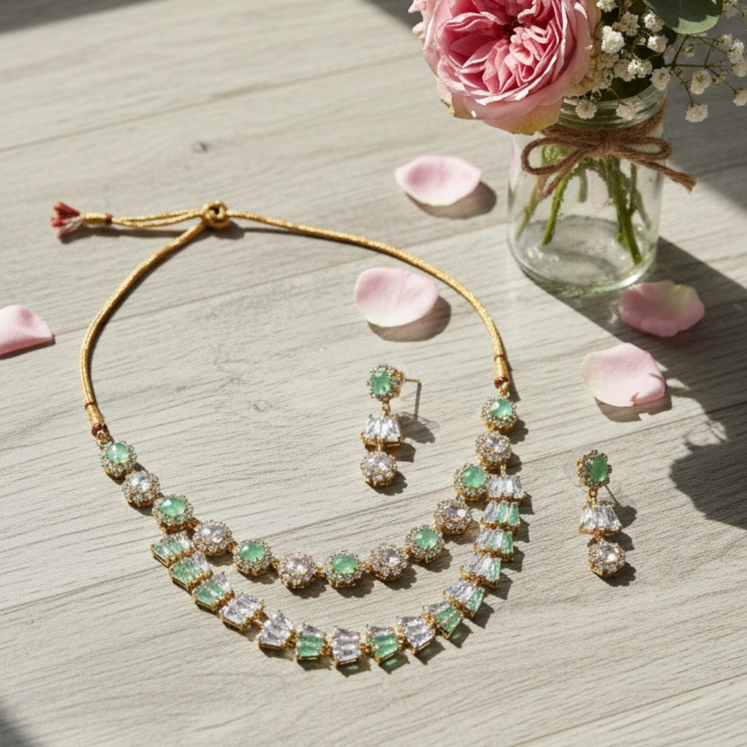 Gold-plated green and white American diamond necklace set with matching earrings on red display stand"