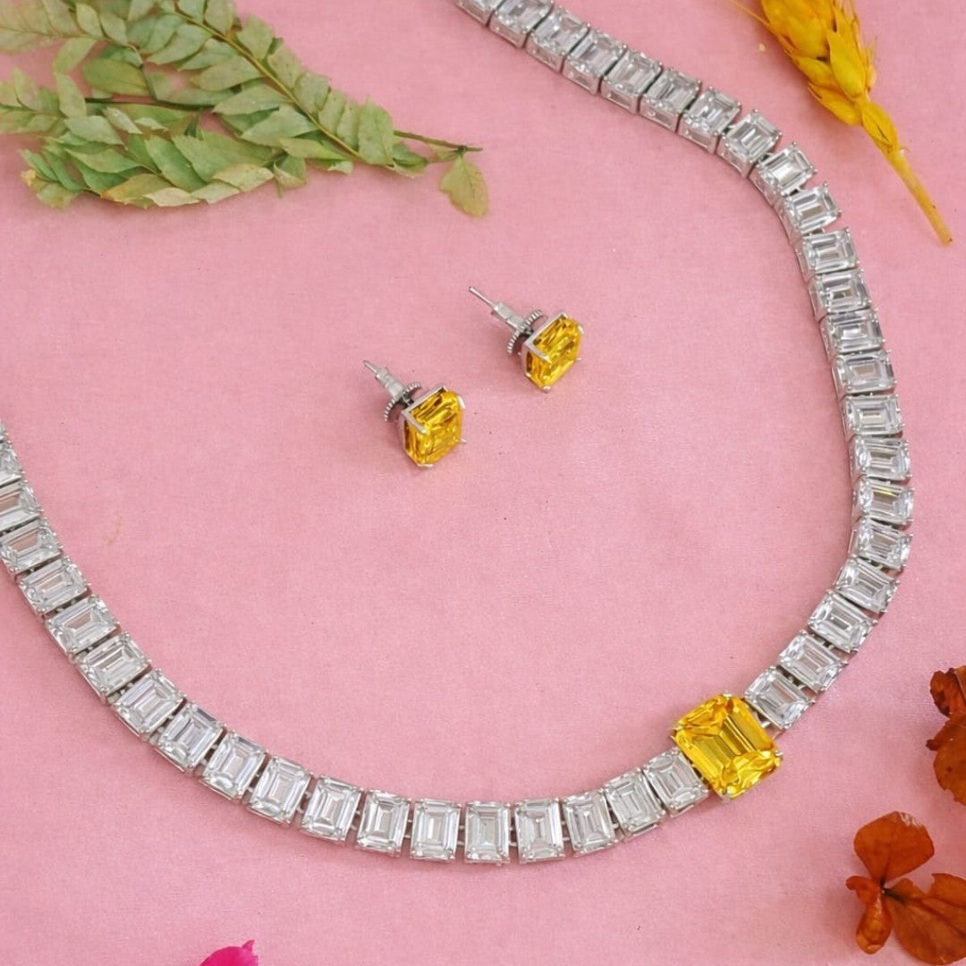 Rhodium American diamond tennis necklace with emerald-cut clear stones, yellow centre stone and matching yellow stud earrings