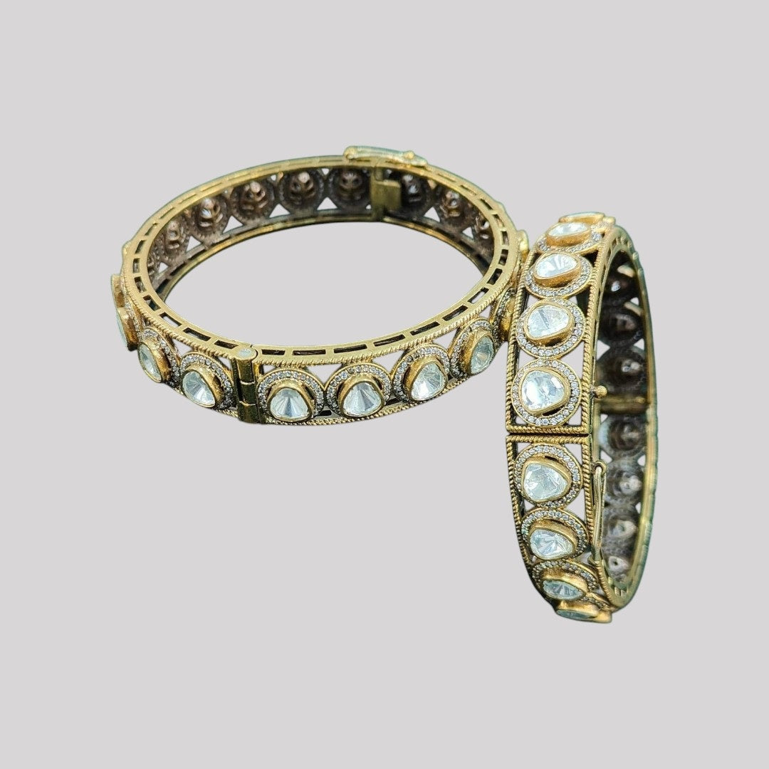 Antique Mehandi polish gold-plated bangles with dome-cut white Kundan stones, placed on a dark green fabric – traditional Indian bridal kada set