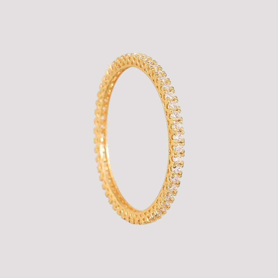 Gold-plated slim bangles set studded with sparkling stones on a light background