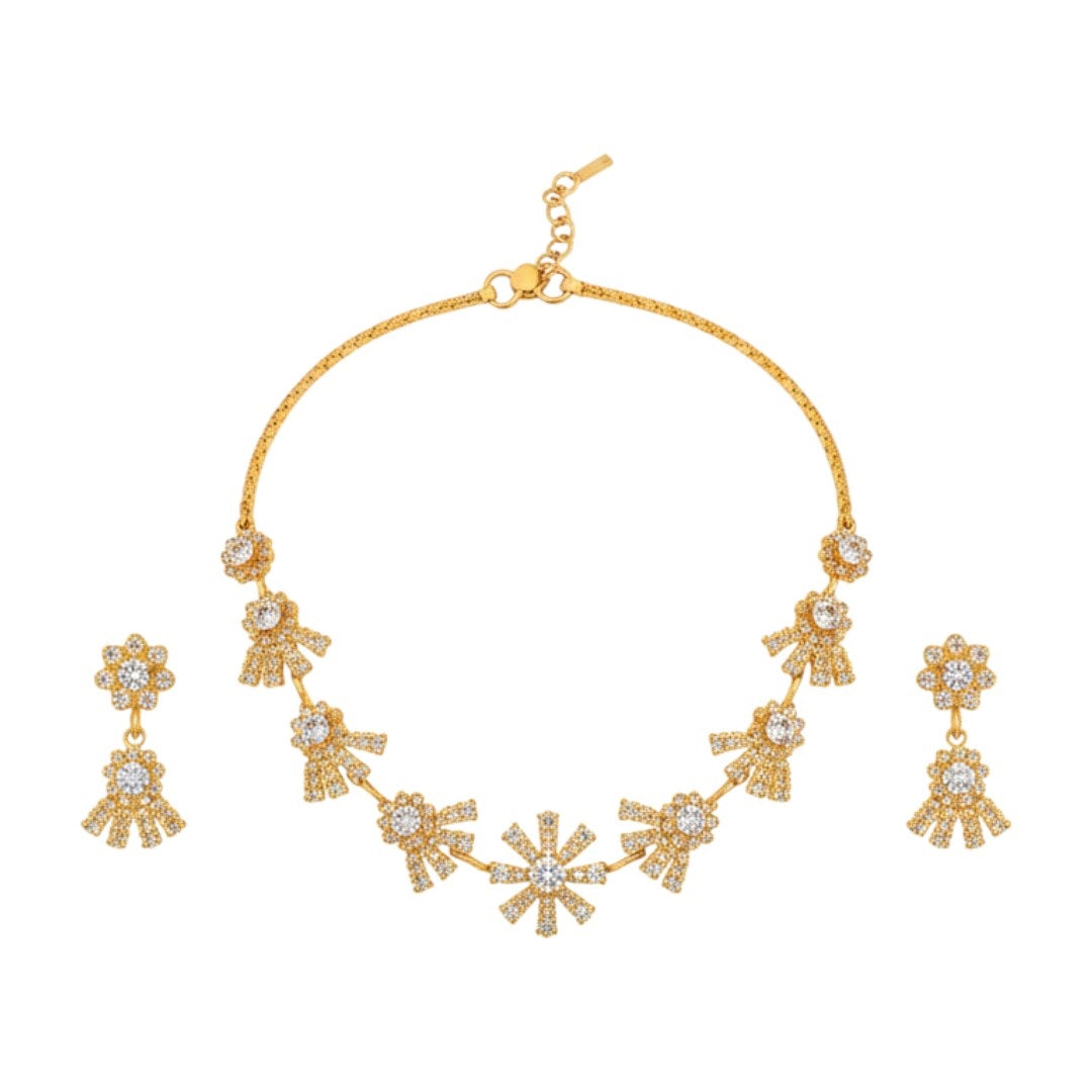 "Gold-plated floral necklace set with stone-studded motifs and matching earrings displayed on black stand – ideal for weddings and festive wear."