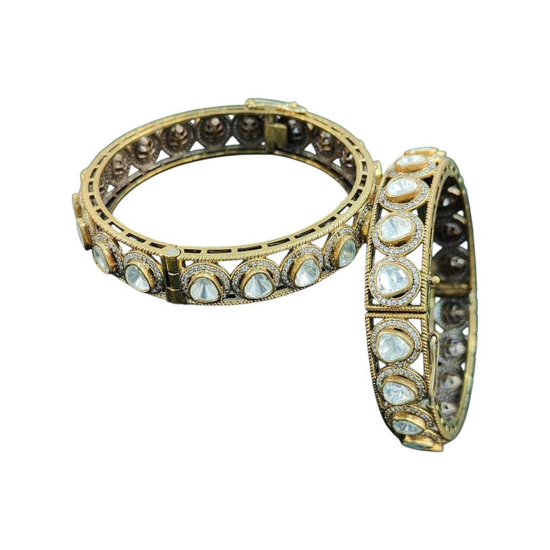 Antique Mehandi polish gold-plated bangles with dome-cut white Kundan stones, placed on a dark green fabric – traditional Indian bridal kada set