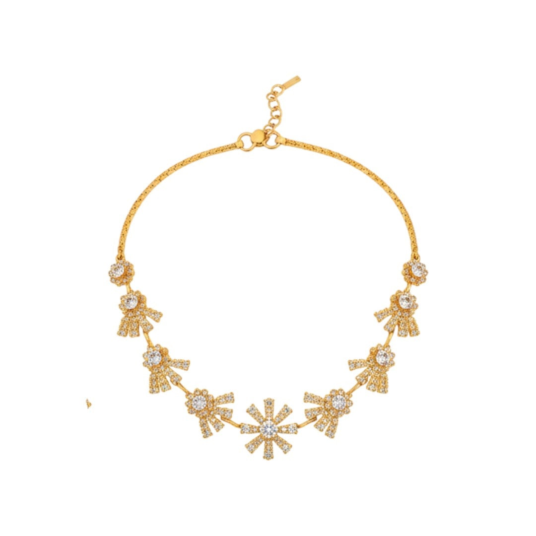 "Gold-plated floral necklace set with stone-studded motifs and matching earrings displayed on black stand – ideal for weddings and festive wear."