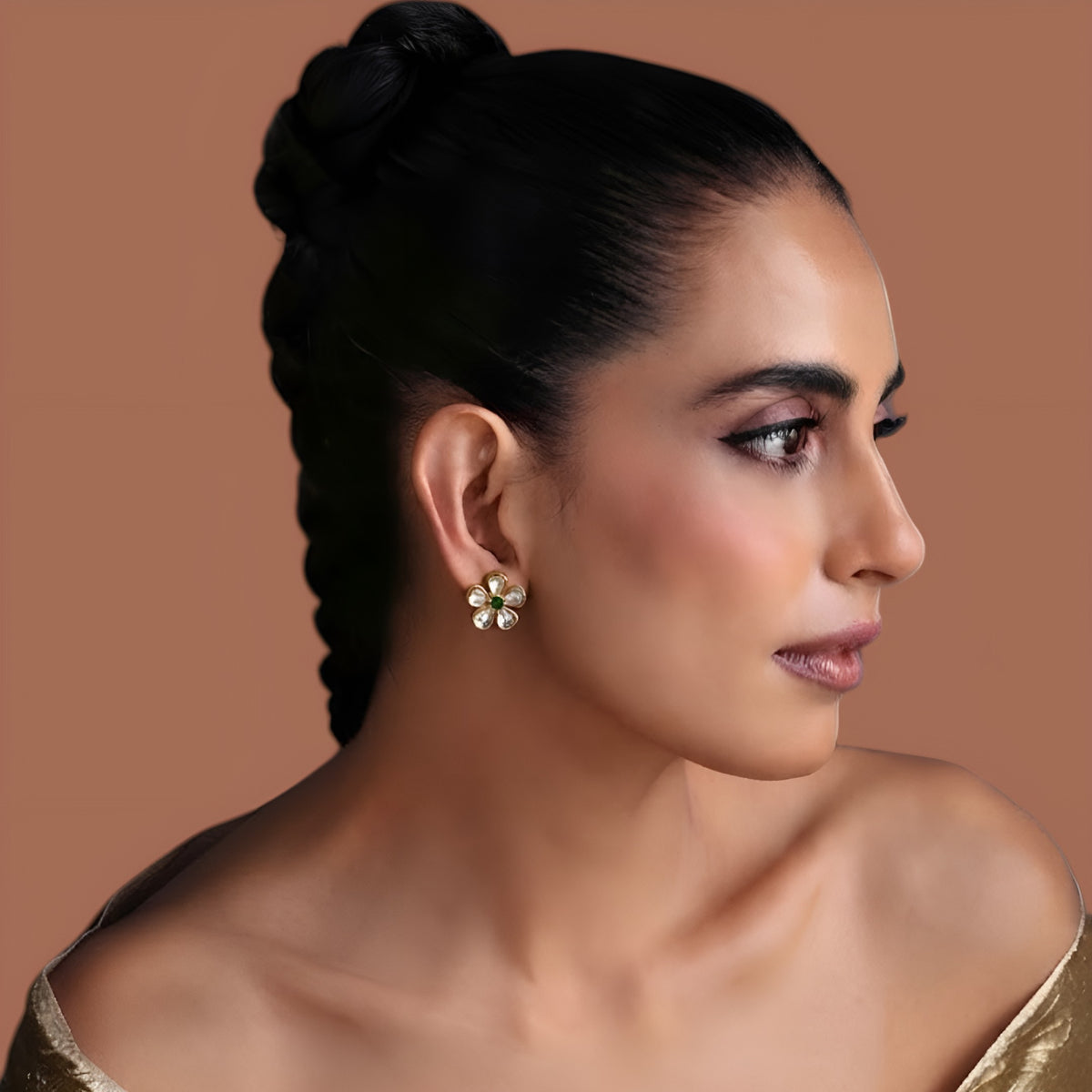Pair of gold-finish kundan floral stud earrings with four clear polki style petals and a small emerald green centre stone