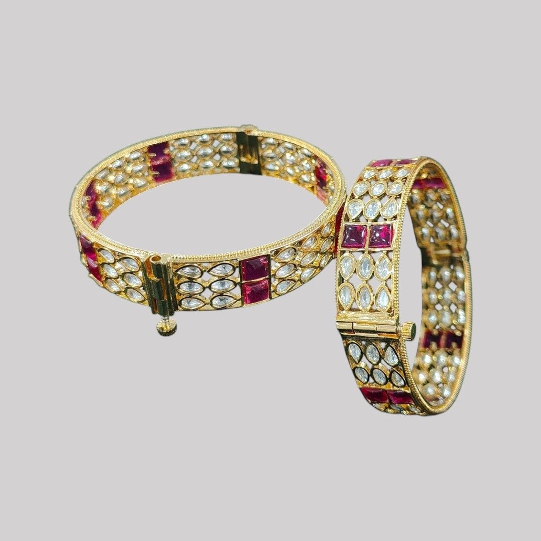 Gold - Plated Designer Bangles with Ruby Red Square & Marquise White Stones - Auraa Trends - Bangles - - Auraa Trends - Gold - plated ethnic bangles featuring marquise white stones and bold ruby red square stones, placed on a wooden surface with white daisies in the background – ideal for bridal and festive wear.