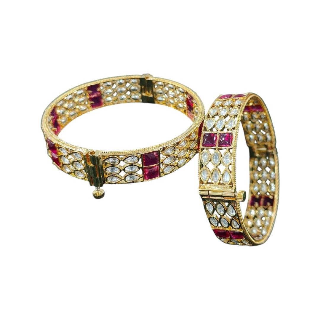 Gold - Plated Designer Bangles with Ruby Red Square & Marquise White Stones - Auraa Trends - Bangles - - Auraa Trends - Gold - plated ethnic bangles featuring marquise white stones and bold ruby red square stones, placed on a wooden surface with white daisies in the background – ideal for bridal and festive wear.
