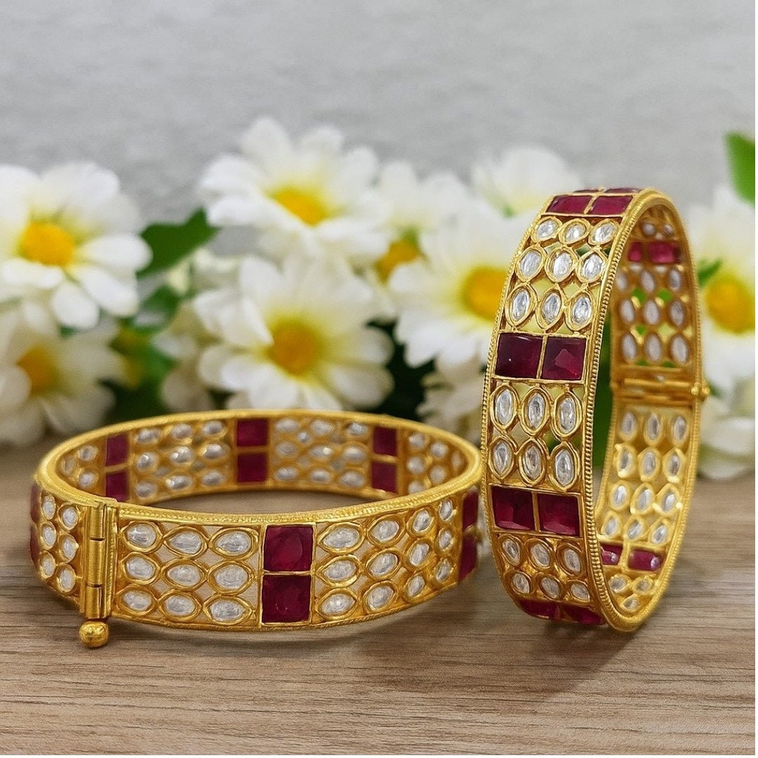 Gold - Plated Designer Bangles with Ruby Red Square & Marquise White Stones - Auraa Trends - Bangles - - Auraa Trends - Gold - plated ethnic bangles featuring marquise white stones and bold ruby red square stones, placed on a wooden surface with white daisies in the background – ideal for bridal and festive wear.