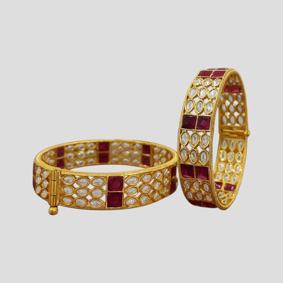Gold - Plated Designer Bangles with Ruby Red Square & Marquise White Stones - Auraa Trends - Bangles - - Auraa Trends - Gold - plated ethnic bangles featuring marquise white stones and bold ruby red square stones, placed on a wooden surface with white daisies in the background – ideal for bridal and festive wear.