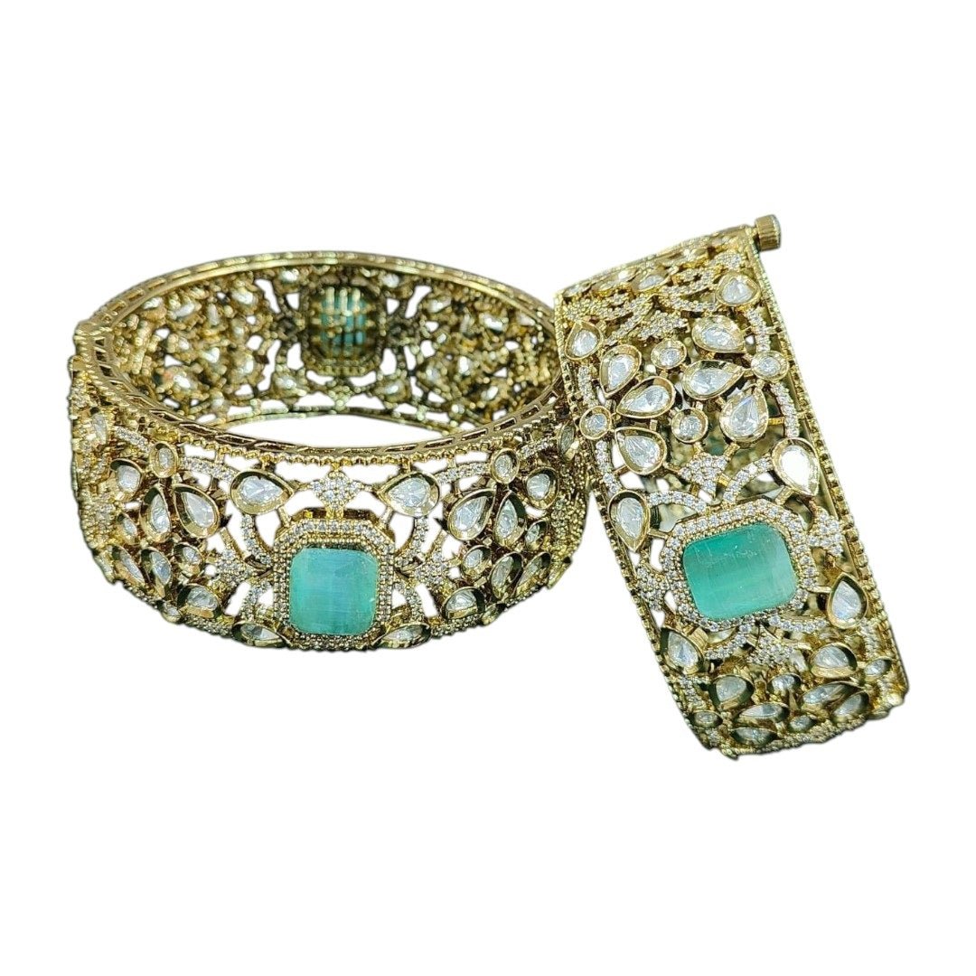 Gold - Plated Designer Broad Bangles with Mint Green Stone & Kundan Detailing - Auraa Trends - Bangles - - Auraa Trends - “Set of two gold - plated broad bangles with pastel mint green stones and intricate kundan - style design, displayed on dark green velvet fabric.”