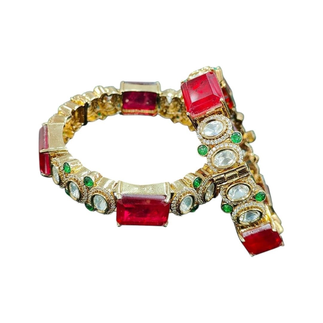 Gold - Plated Red Stone Bangles with Kundan & Green Detailing - Auraa Trends - Bangles - - Auraa Trends - “Gold - plated traditional bangles with large red stones, kundan detailing, and green enamel accents – set of 2 displayed on white background with flowers.”