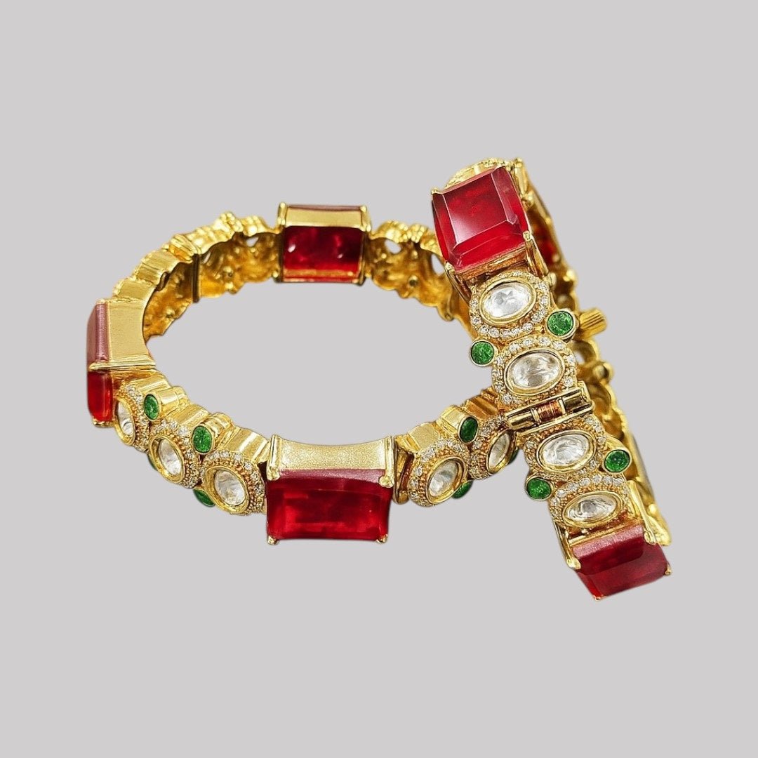 Gold - Plated Red Stone Bangles with Kundan & Green Detailing - Auraa Trends - Bangles - - Auraa Trends - “Gold - plated traditional bangles with large red stones, kundan detailing, and green enamel accents – set of 2 displayed on white background with flowers.”