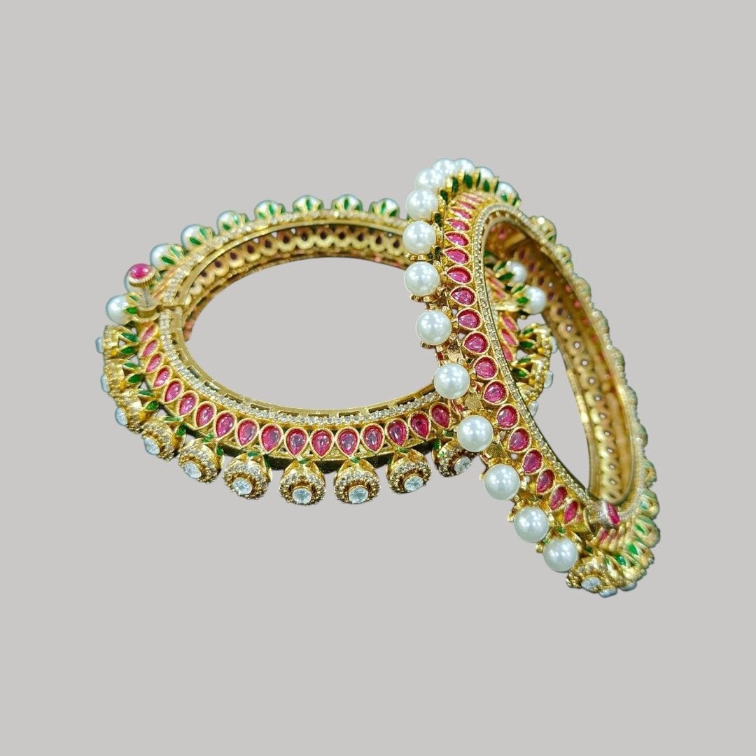 Gold - Plated Traditional Red Enamel Bangles with Pearl & Kundan Detailing - Auraa Trends - Bangles - - Auraa Trends - “Traditional gold - plated bangles with red enamel, pearl beading, kundan stones, and green detailing – set of 2 on green velvet background.”