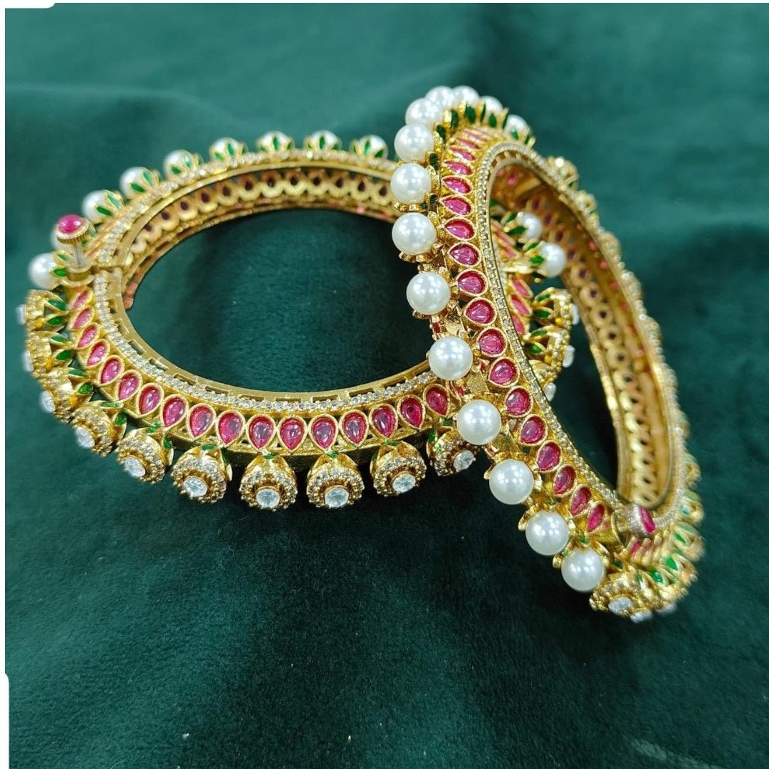 Gold - Plated Traditional Red Enamel Bangles with Pearl & Kundan Detailing - Auraa Trends - Bangles - - Auraa Trends - “Traditional gold - plated bangles with red enamel, pearl beading, kundan stones, and green detailing – set of 2 on green velvet background.”