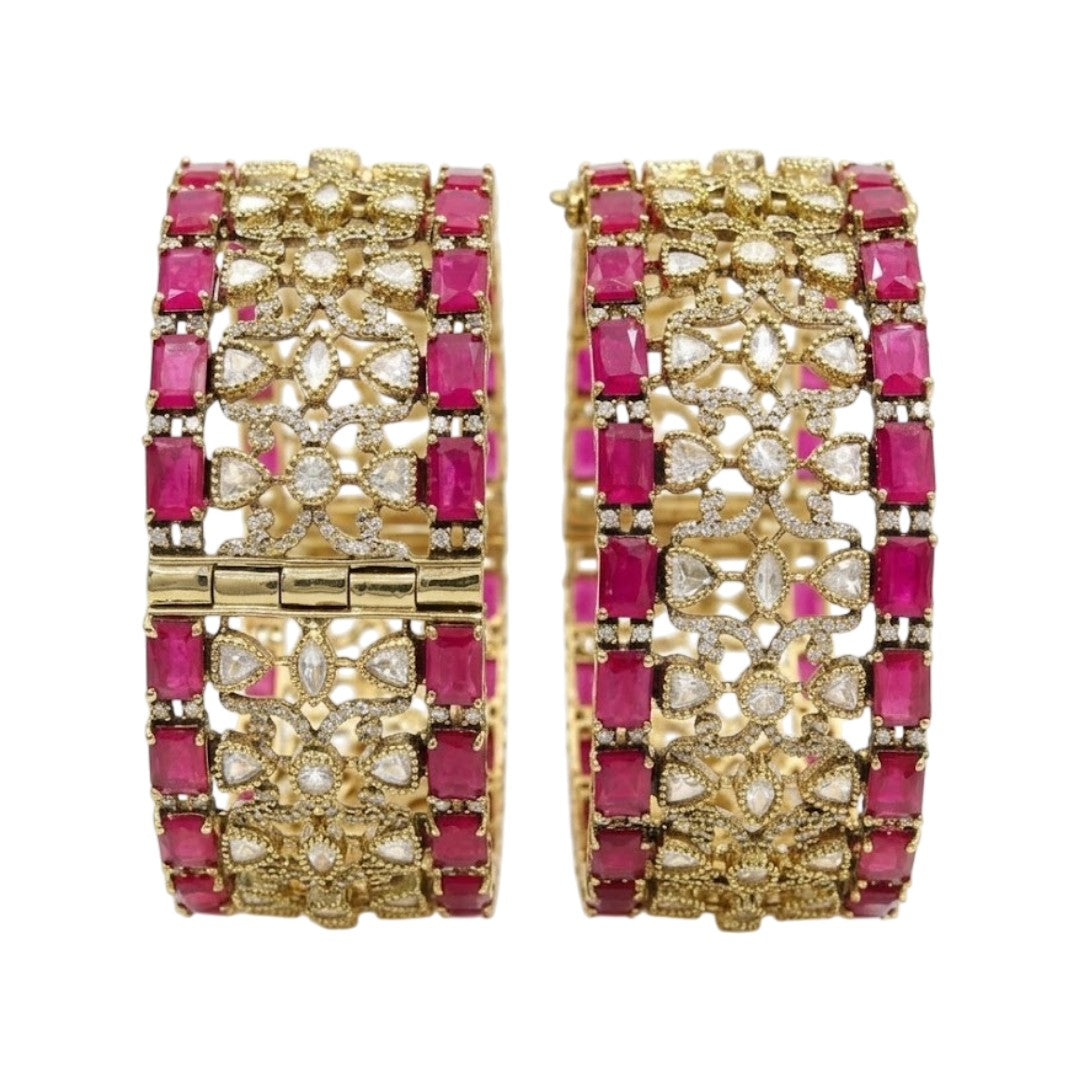 Pair of antique gold-finish wide kada bangles with ruby-pink rectangular stones, polki-style clear stones, and Victorian-style American diamond scrollwork