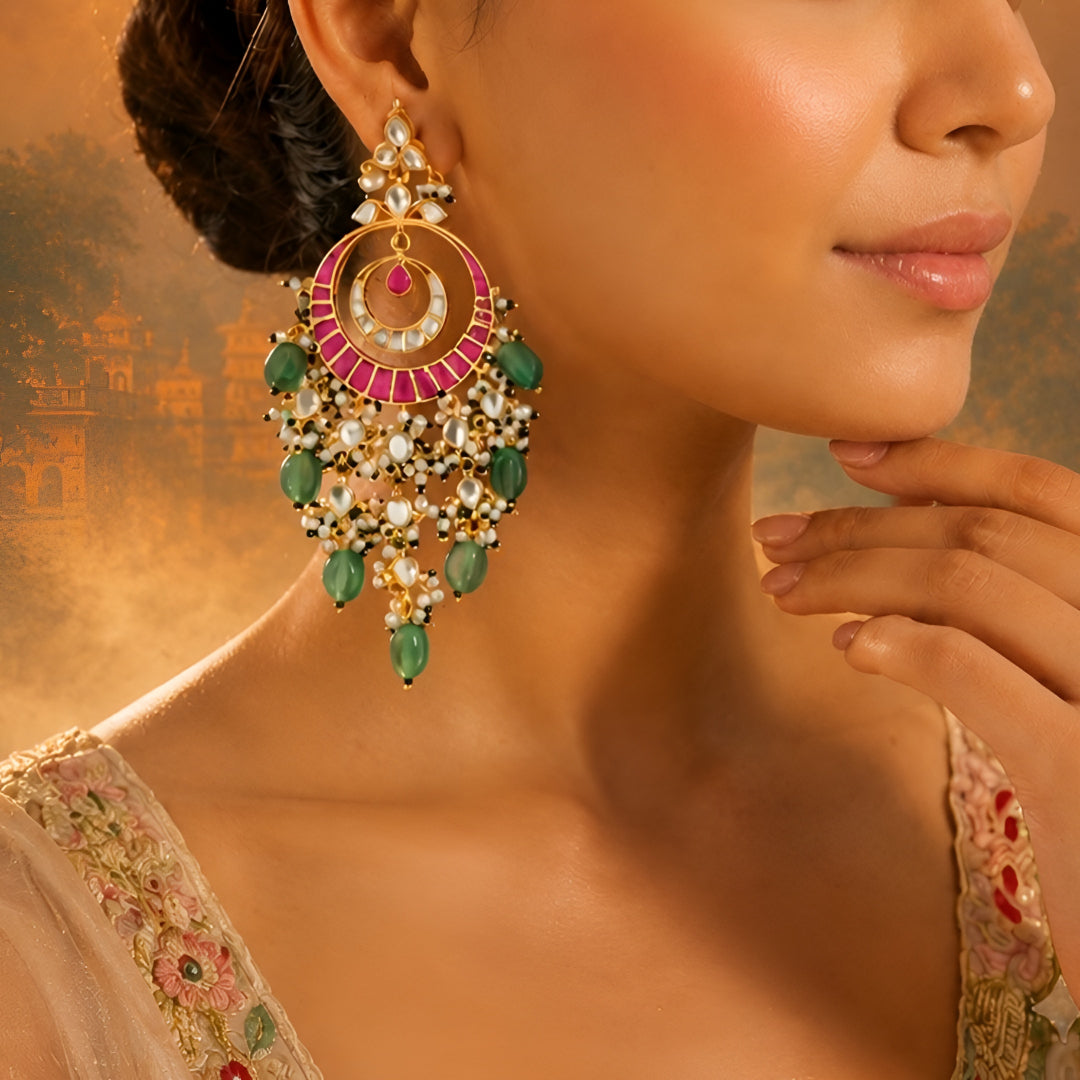 Pink meenakari Kundan chandbali earrings with green stone beads and pearl drops in antique gold finish for women.