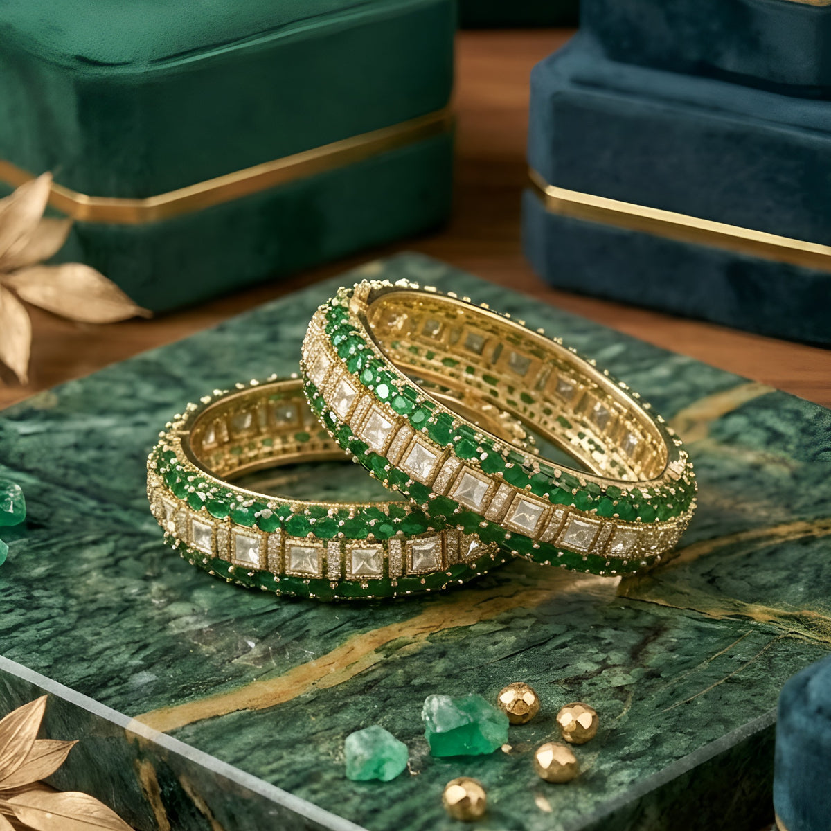 Pair of gold-finish openable kada bangles with emerald-green oval stones, a centre row of polki-style clear square stones, and American diamond detailing