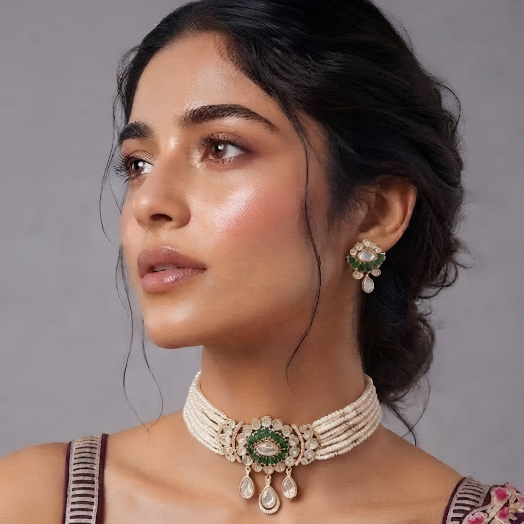 Green kundan pearl choker necklace set with floral centre pendant, kundan teardrop drops and matching floral earrings on a grey display bust