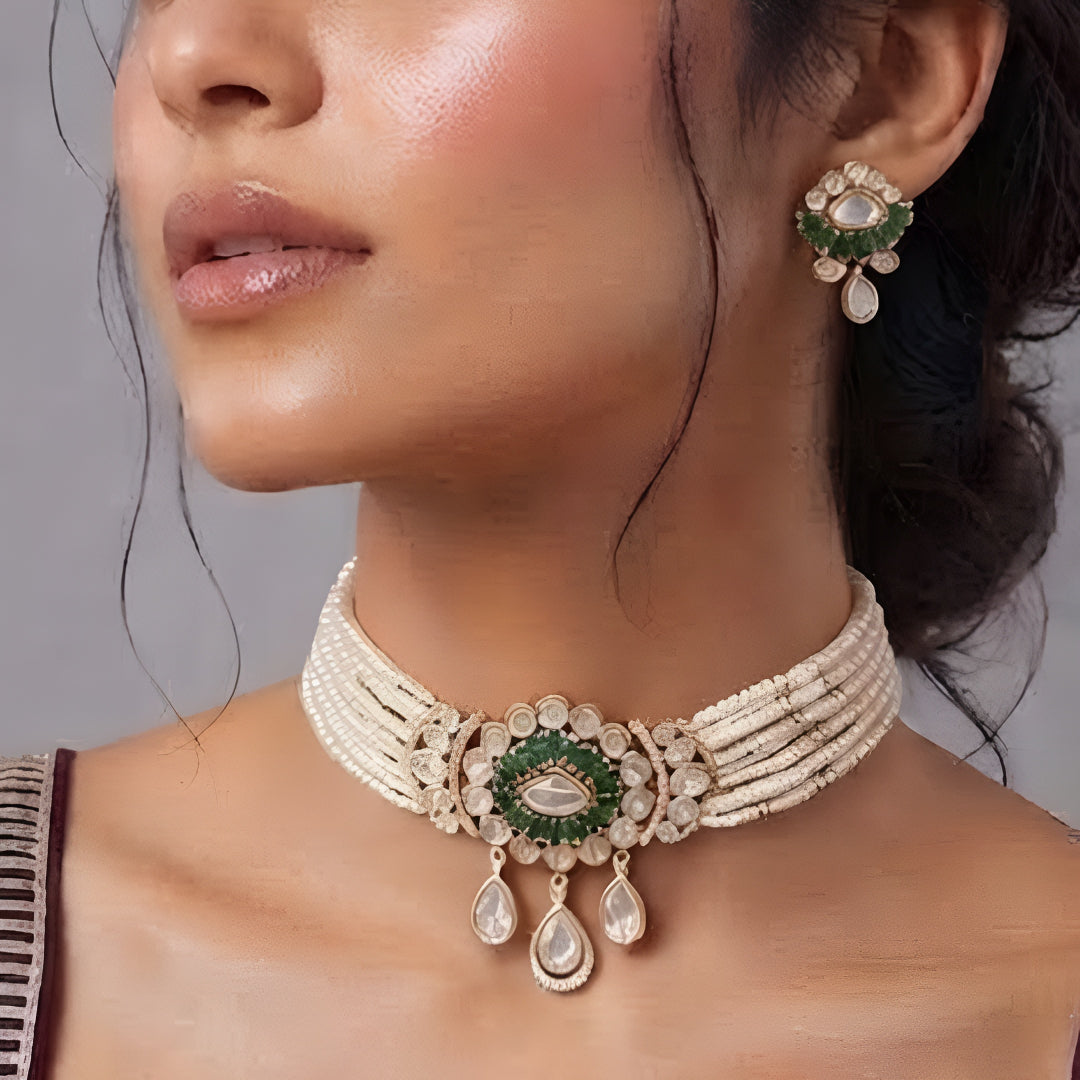 Green kundan pearl choker necklace set with floral centre pendant, kundan teardrop drops and matching floral earrings on a grey display bust