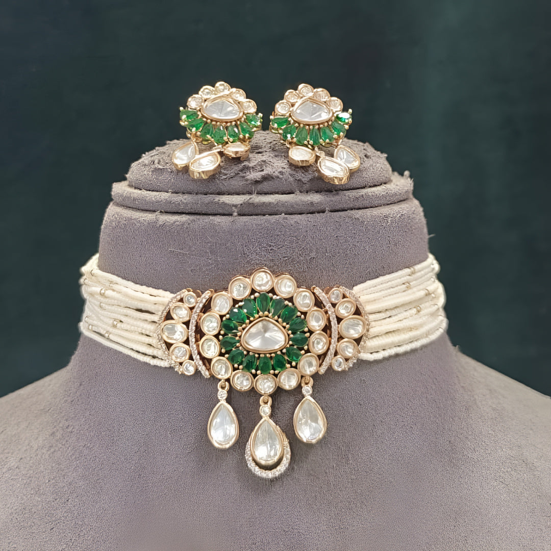 Green kundan pearl choker necklace set with floral centre pendant, kundan teardrop drops and matching floral earrings on a grey display bust