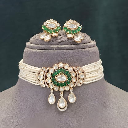 Green kundan pearl choker necklace set with floral centre pendant, kundan teardrop drops and matching floral earrings on a grey display bust