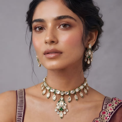 Gold-tone green meenakari kundan necklace set with round centre pendant, leaf-shaped drops and matching drop earrings on a grey display bust