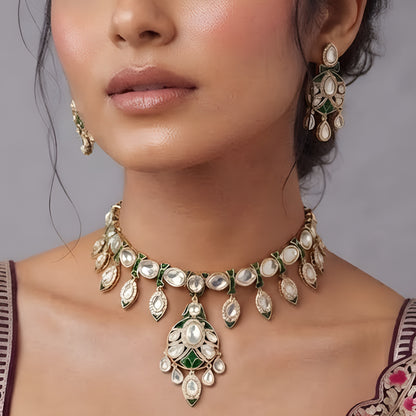 Gold-tone green meenakari kundan necklace set with round centre pendant, leaf-shaped drops and matching drop earrings on a grey display bust