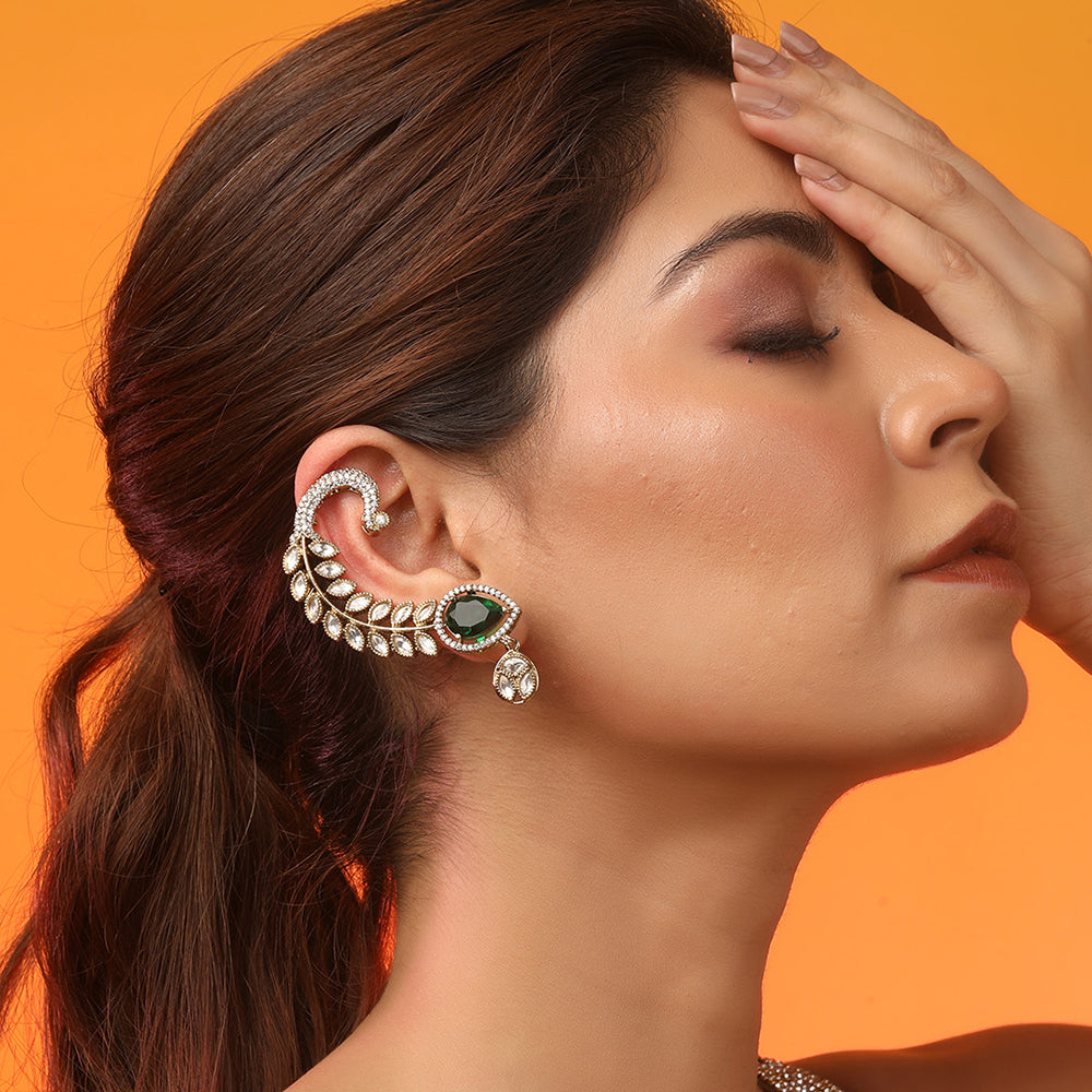 Gold plated American diamond ear cuff earrings with green teardrop stone and leaf design on white background
