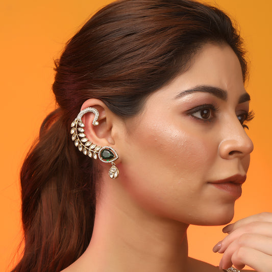 Gold plated American diamond ear cuff earrings with green teardrop stone and leaf design on white background