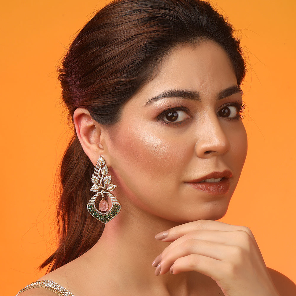 Gold plated American diamond earrings with leaf design, green stones and pink drop hanging centerpiece on white background