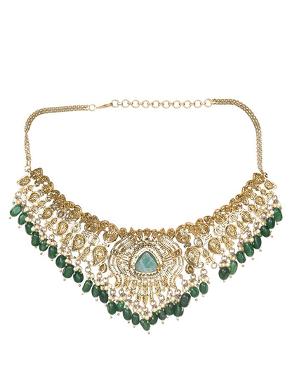 Detailed gold-toned statement necklace with intricate white stone embellishments and a prominent green teardrop centerpiece, finished with dangling green beads and pearls, paired with matching ornate drop earrings, displayed on a plain light background.