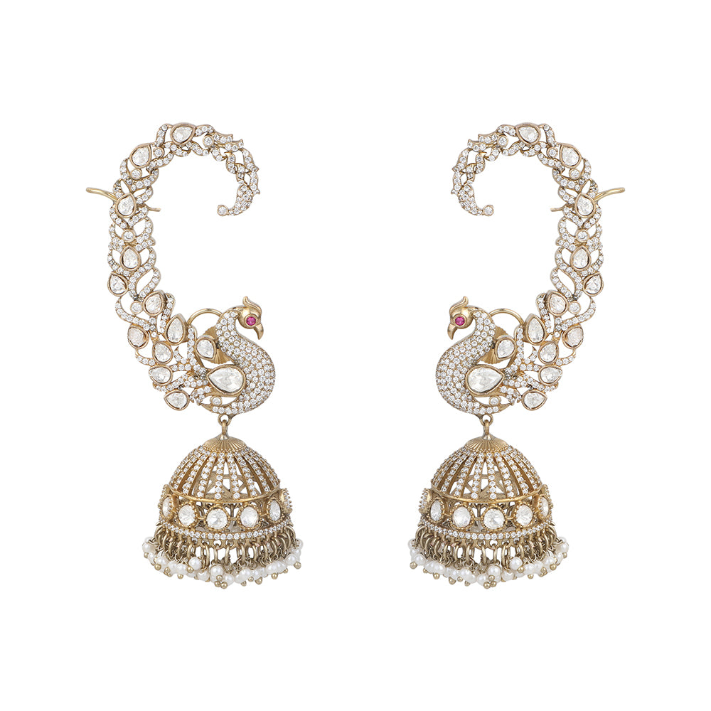 Gold plated peacock design jhumka earrings with American diamonds and pearl drops on white background