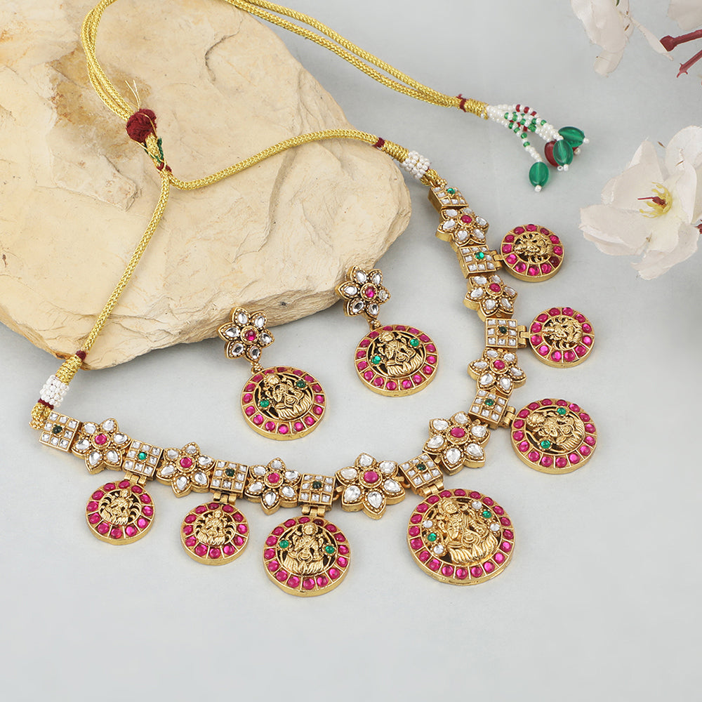 Gold plated Lakshmi coin necklace set with pink stones and matching earrings on white background