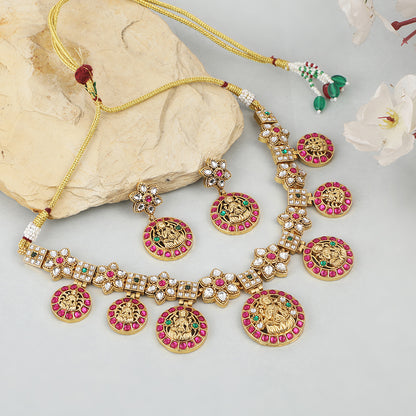 Gold plated Lakshmi coin necklace set with pink stones and matching earrings on white background