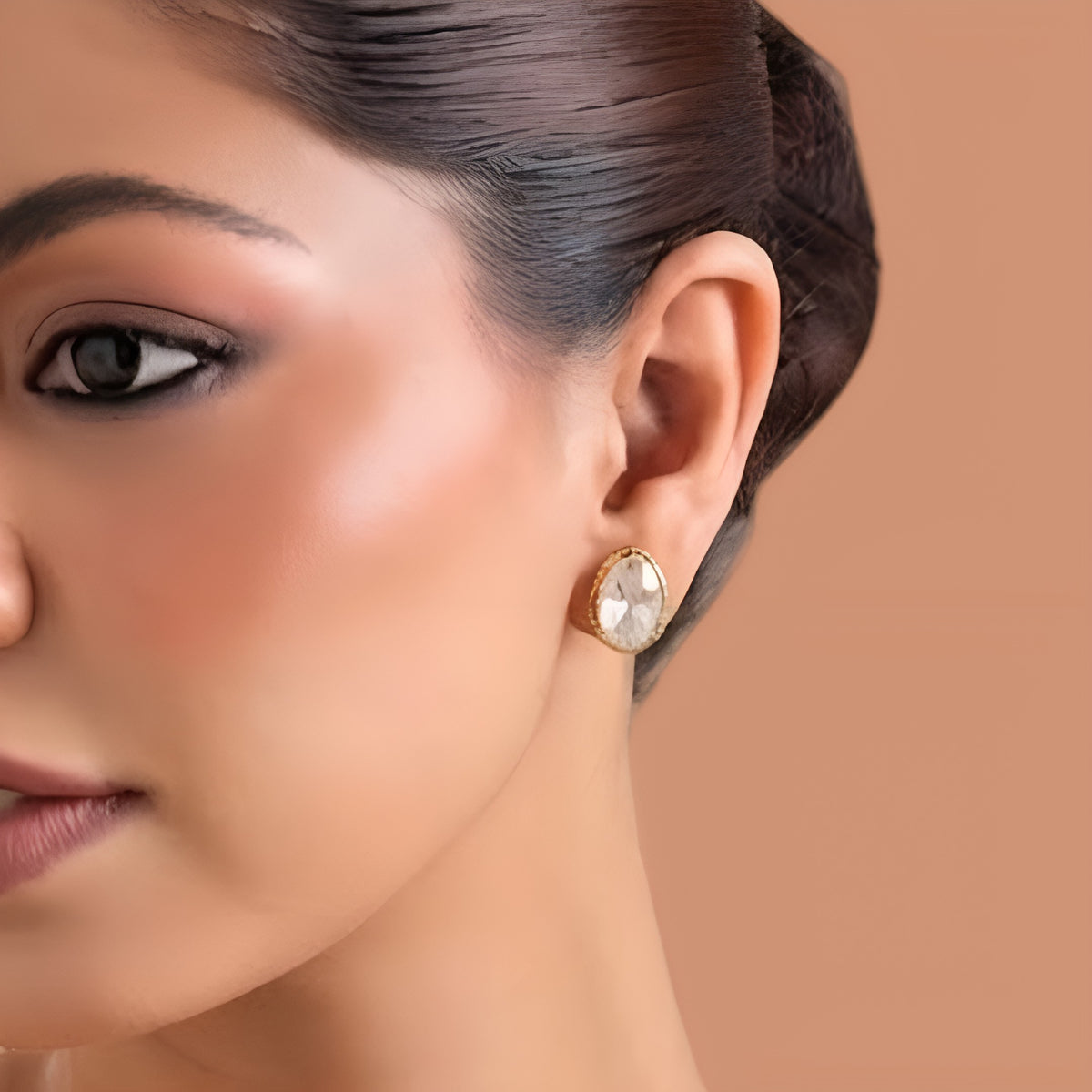 Gold-finish oval kundan polki stud earrings with a clear starburst cut stone in a gold bezel