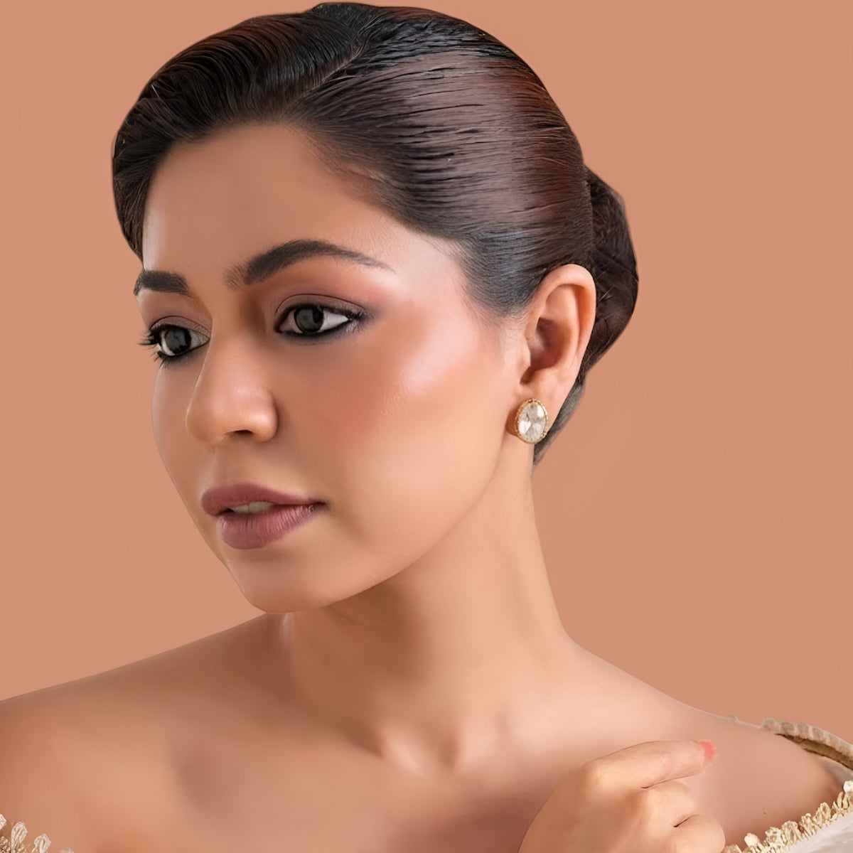 Gold-finish oval kundan polki stud earrings with a clear starburst cut stone in a gold bezel