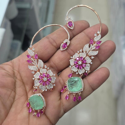 Rose gold American diamond ear cuff earrings with ruby pink pear stones and mint green cushion-cut drops, held in hand