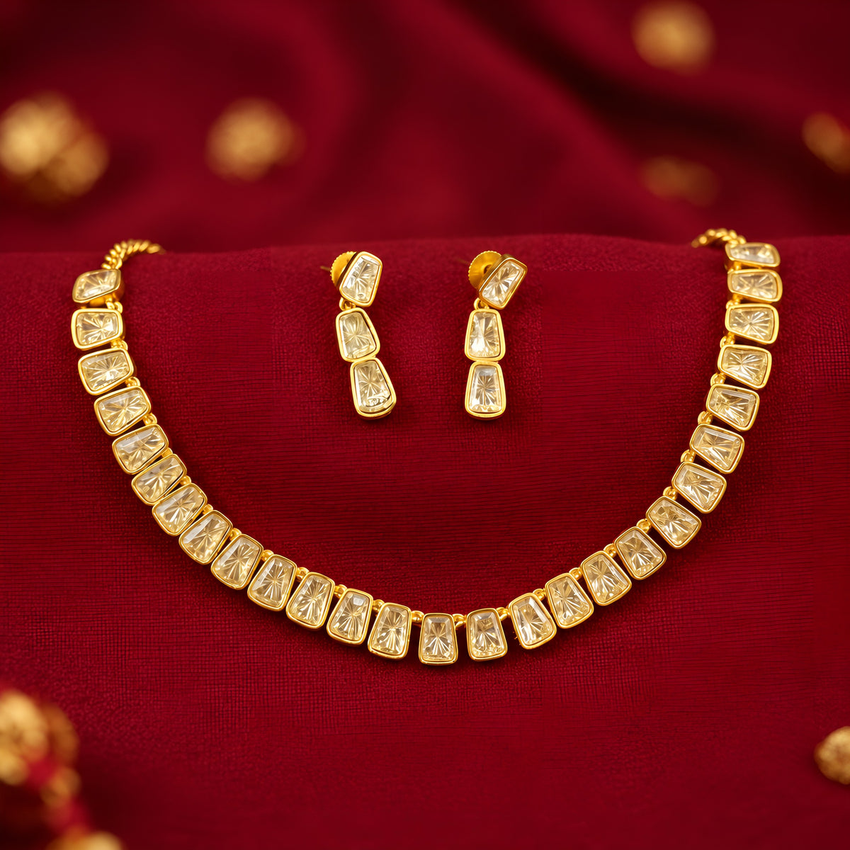 Gold plated polki kundan necklace set with matching drop earrings on red fabric