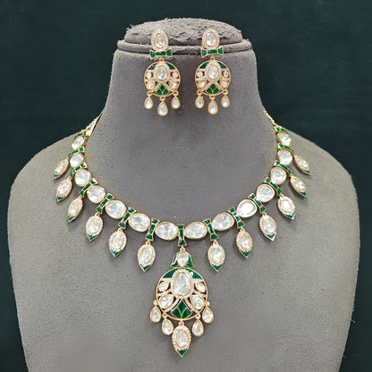 Gold-tone green meenakari kundan necklace set with round centre pendant, leaf-shaped drops and matching drop earrings on a grey display bust