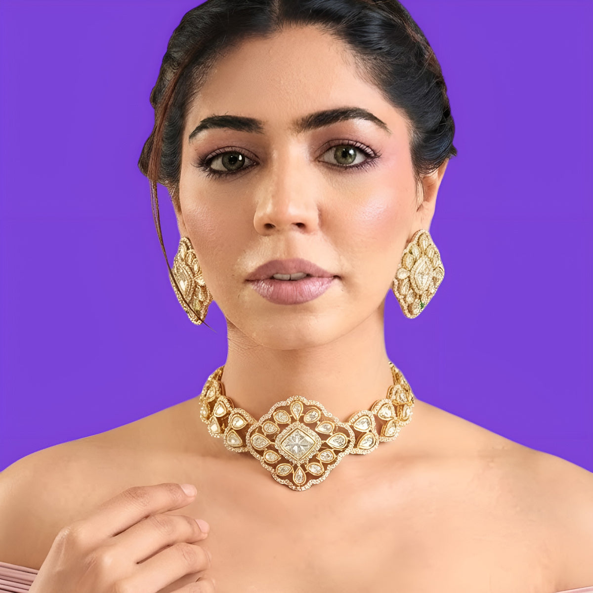 Gold plated polki kundan choker necklace set with matching diamond-shaped stud earrings held in hand