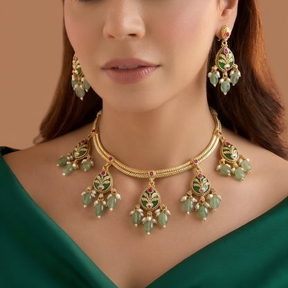 Antique gold plated necklace set with dark green pear medallions, pink stones, mint green bead and pearl drops and matching earrings on a blue bust