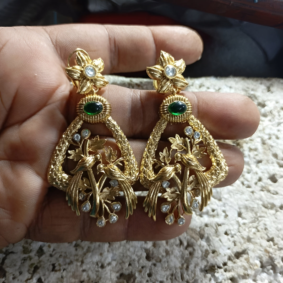 "Antique matte gold bird motif earrings with emerald green stone and CZ accents, floral stud design on dark background"