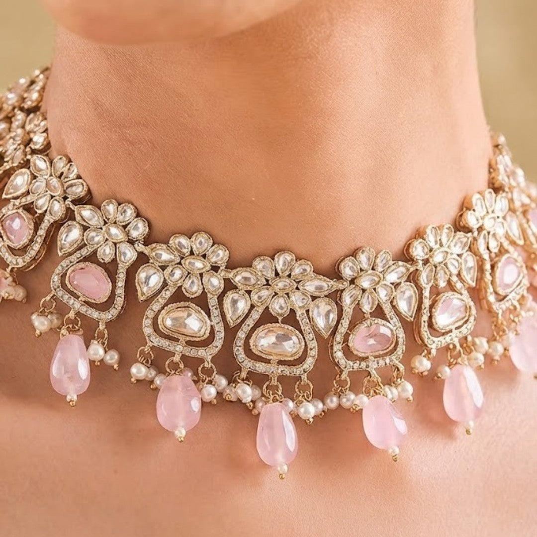 Gold-plated floral Kundan choker necklace set with pink beads, pearl drops, and matching earrings for bridal, wedding, and festive wear.