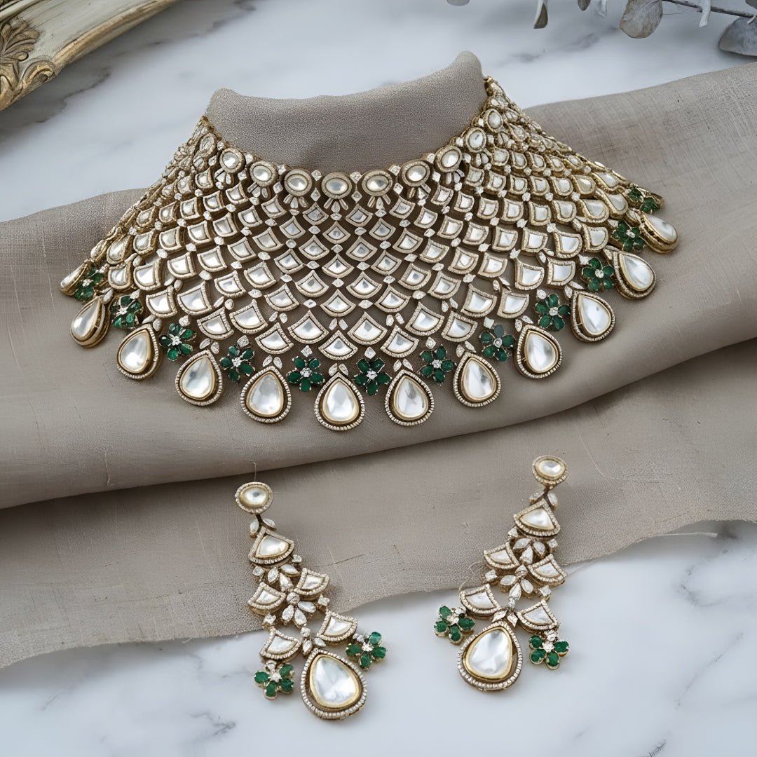 Shop this grand Kundan net-style choker with emerald floral accents & chandelier earrings. Perfect for bridal & festive occasions. Order now!